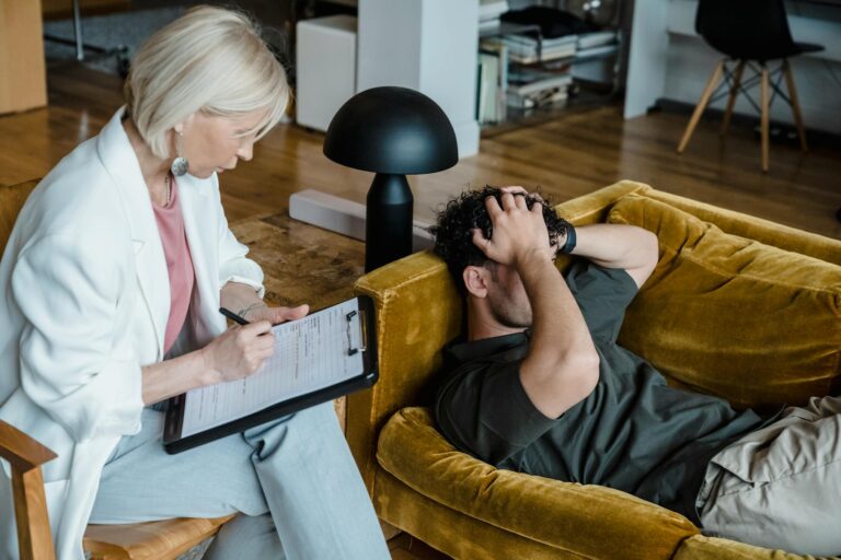 A therapist conducts a session with a client discussing mental health in a cozy office setting.